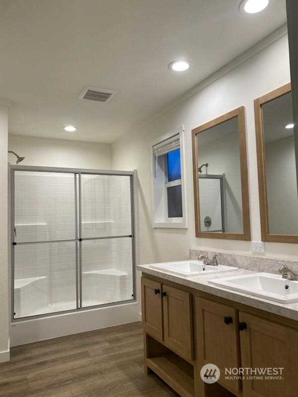 bathroom with a shower with door, hardwood / wood-style floors, and vanity