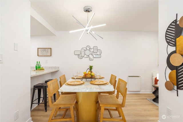 dining area with light wood-type flooring and a notable chandelier