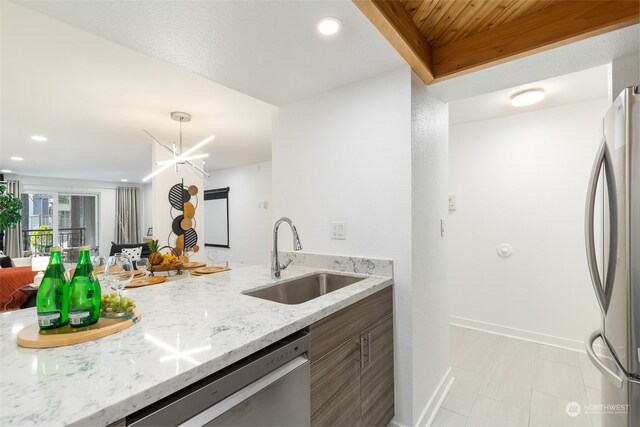 kitchen featuring sink, a notable chandelier, light stone counters, and appliances with stainless steel finishes