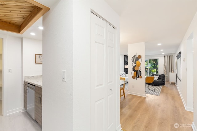 corridor with light hardwood / wood-style floors and wooden ceiling