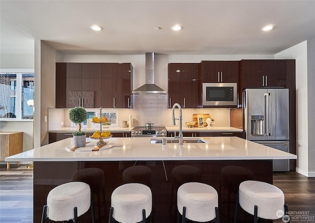 kitchen with appliances with stainless steel finishes, light countertops, wall chimney exhaust hood, and a sink