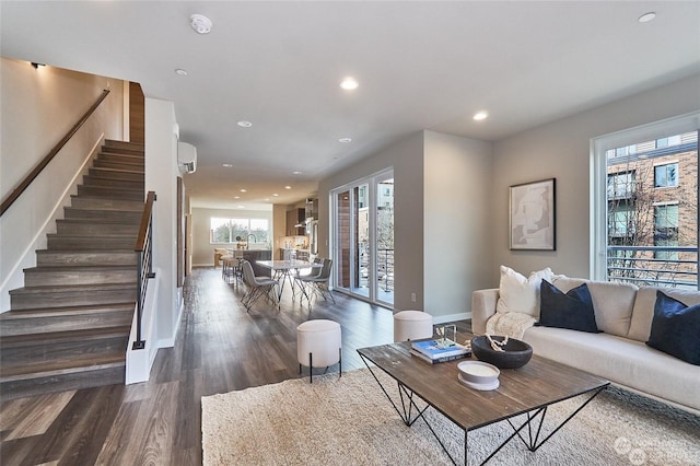 living room featuring baseboards, recessed lighting, dark wood-style flooring, stairs, and a wall mounted air conditioner