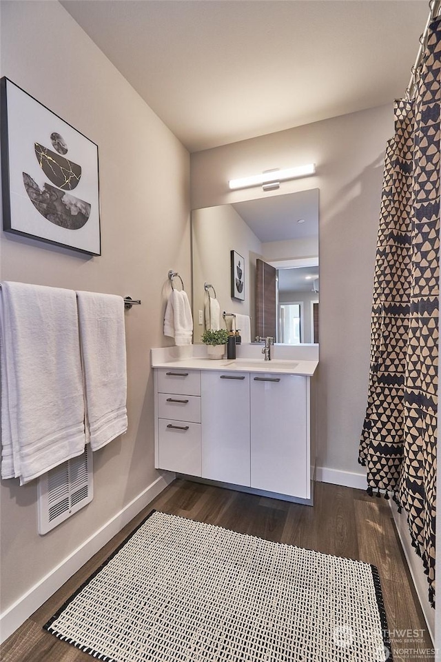 full bathroom with baseboards, a shower with curtain, wood finished floors, and vanity