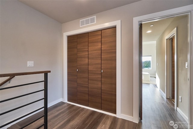 unfurnished bedroom with a closet, visible vents, baseboards, and dark wood-style flooring