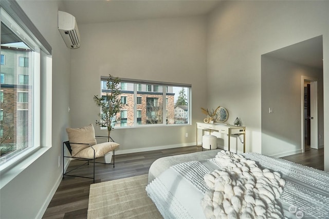 bedroom with wood finished floors, baseboards, a towering ceiling, and a wall mounted AC