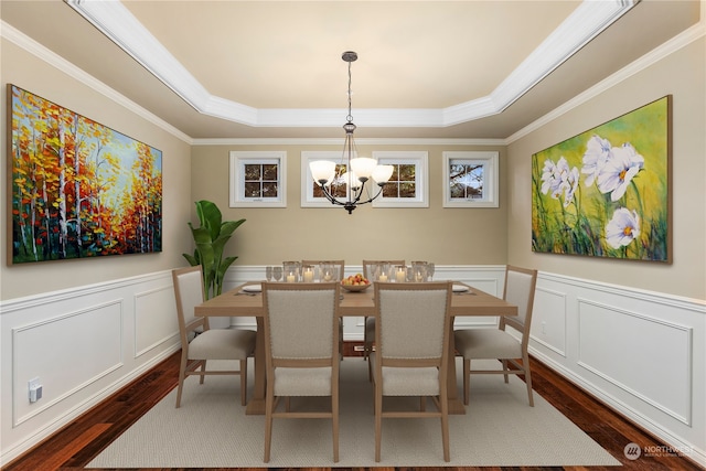 dining room with a raised ceiling, dark hardwood / wood-style flooring, crown molding, and a notable chandelier