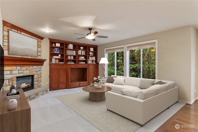 living room with ceiling fan, light colored carpet, and a stone fireplace