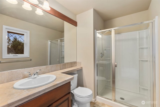 bathroom featuring a shower with shower door, toilet, and vanity