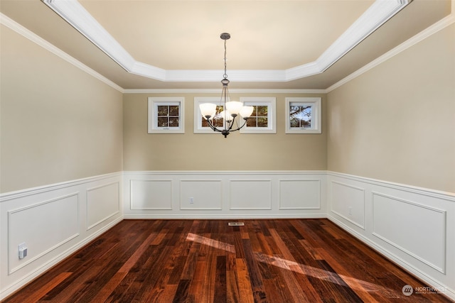 unfurnished dining area with dark hardwood / wood-style floors, an inviting chandelier, ornamental molding, and a raised ceiling