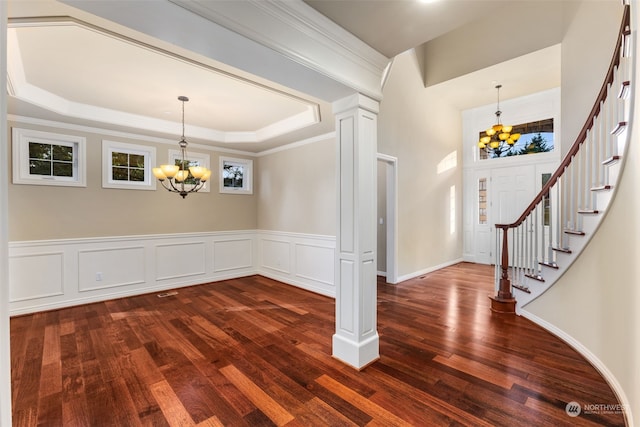 foyer with a raised ceiling, dark hardwood / wood-style flooring, an inviting chandelier, and ornamental molding