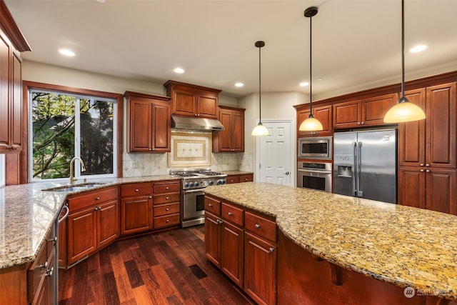 kitchen with decorative light fixtures, sink, backsplash, and high quality appliances