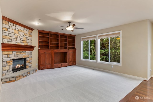 unfurnished living room with ceiling fan, light colored carpet, and a fireplace