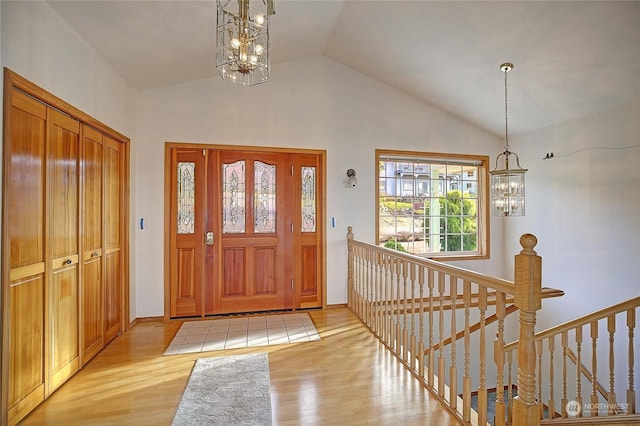 entrance foyer with a notable chandelier, vaulted ceiling, and light hardwood / wood-style flooring