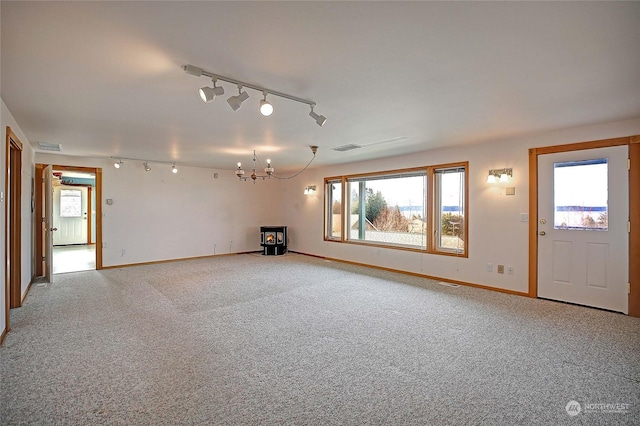 unfurnished living room featuring an inviting chandelier, carpet floors, and rail lighting