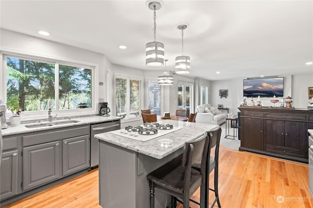 kitchen with a center island, light stone countertops, dishwasher, hanging light fixtures, and sink