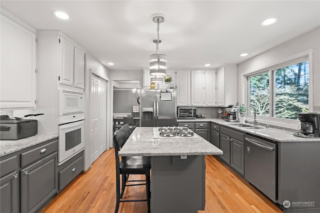 kitchen with sink, a center island, white cabinetry, and appliances with stainless steel finishes