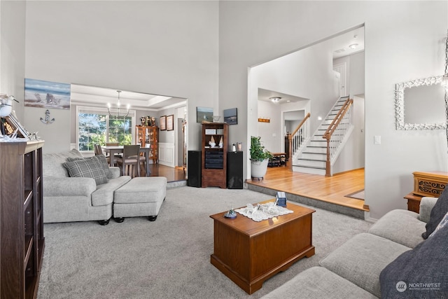 carpeted living room with an inviting chandelier and a tray ceiling