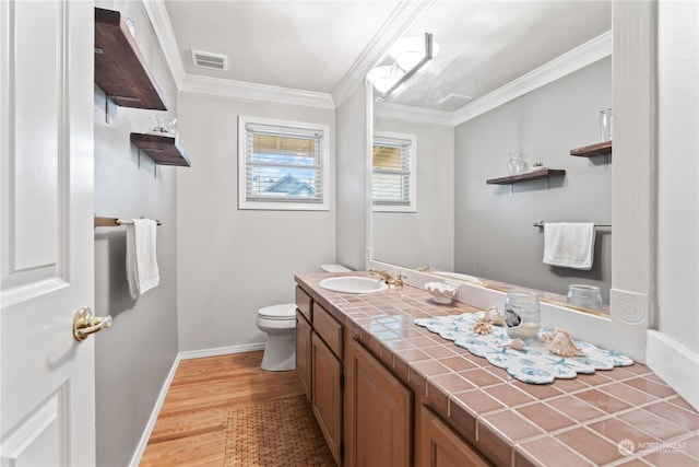 bathroom featuring wood-type flooring, toilet, vanity, and crown molding