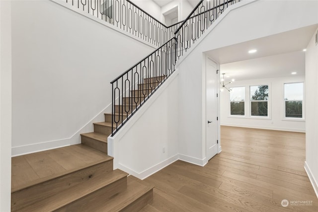 stairs with an inviting chandelier and hardwood / wood-style flooring