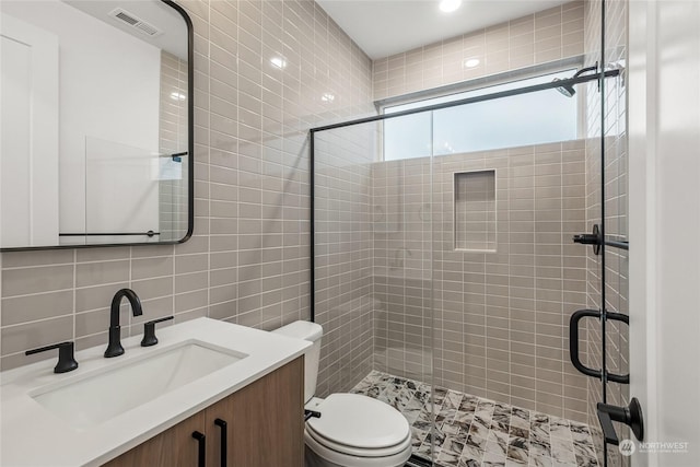 bathroom with a shower with door, vanity, decorative backsplash, and toilet