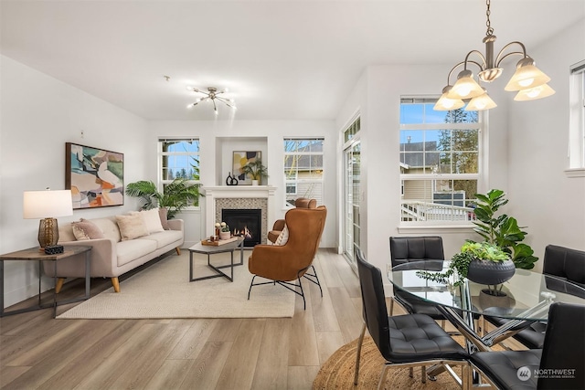 interior space featuring a tiled fireplace, a notable chandelier, and light hardwood / wood-style floors