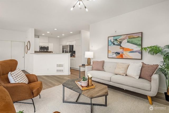 living room with light hardwood / wood-style floors and an inviting chandelier