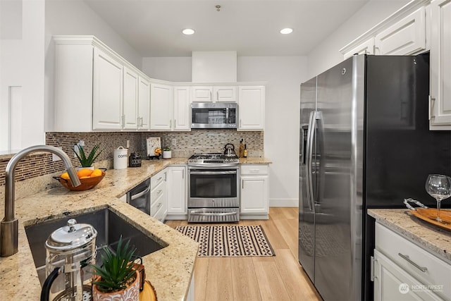 kitchen with appliances with stainless steel finishes, white cabinets, tasteful backsplash, and sink