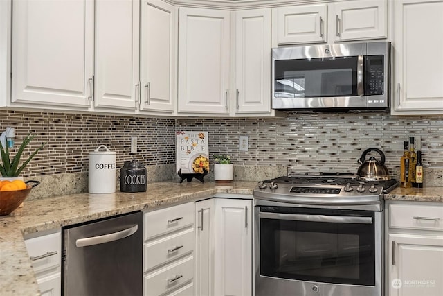 kitchen featuring stainless steel appliances, decorative backsplash, white cabinetry, and light stone countertops