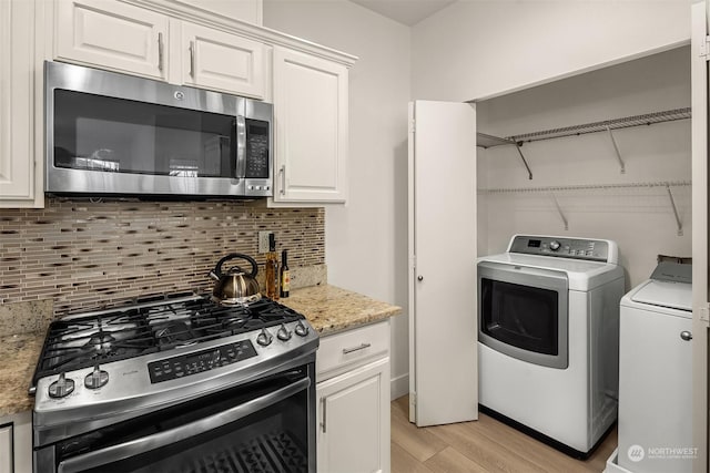 clothes washing area featuring light wood-type flooring and washing machine and clothes dryer