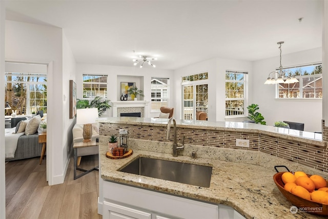 kitchen featuring an inviting chandelier, white cabinetry, decorative backsplash, hanging light fixtures, and sink