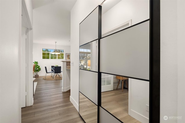 hall with a chandelier and light hardwood / wood-style floors