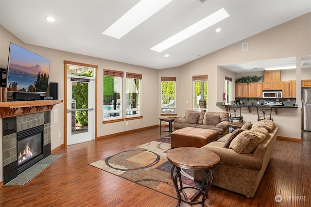 living room featuring vaulted ceiling, dark wood-type flooring, and a tile fireplace