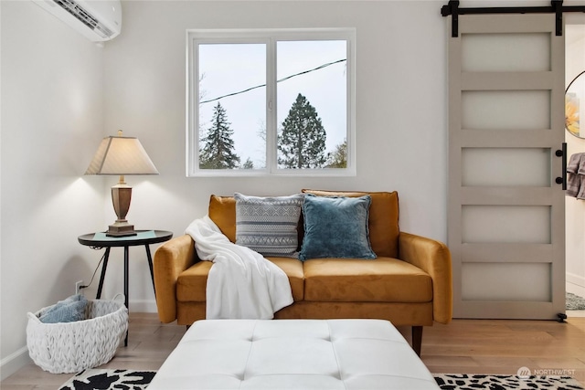 living area with built in features, light hardwood / wood-style flooring, a wall mounted AC, and a barn door