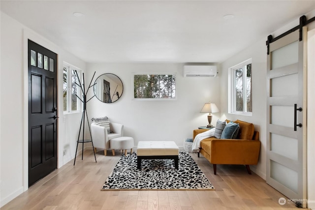 sitting room with light hardwood / wood-style flooring, a wall unit AC, and a barn door