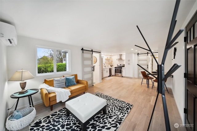 living room featuring a barn door, light hardwood / wood-style floors, and a wall mounted air conditioner