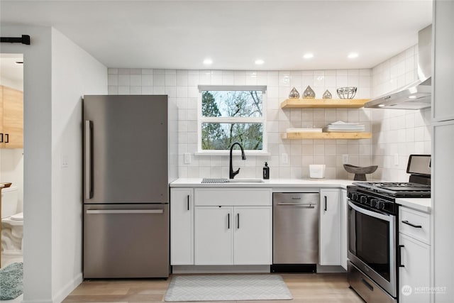 kitchen with light wood-type flooring, appliances with stainless steel finishes, white cabinets, and sink