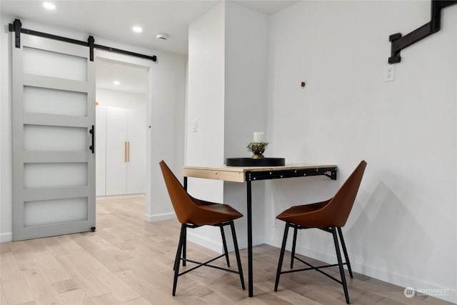 dining area featuring built in features, a barn door, and light wood-type flooring