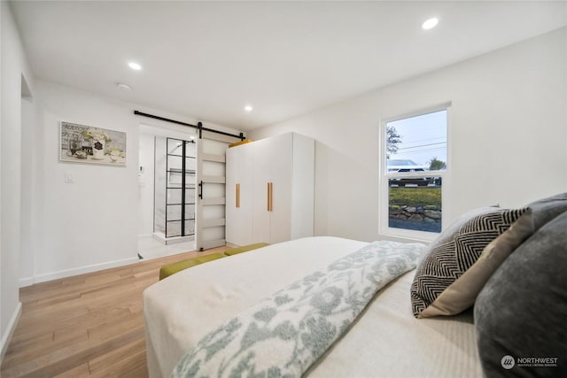 bedroom featuring a barn door and light hardwood / wood-style flooring