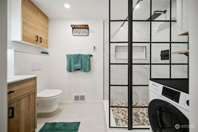 bathroom with washer / dryer, tile patterned flooring, vanity, toilet, and a tile shower