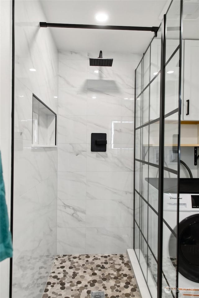 bathroom featuring tiled shower and washer / clothes dryer