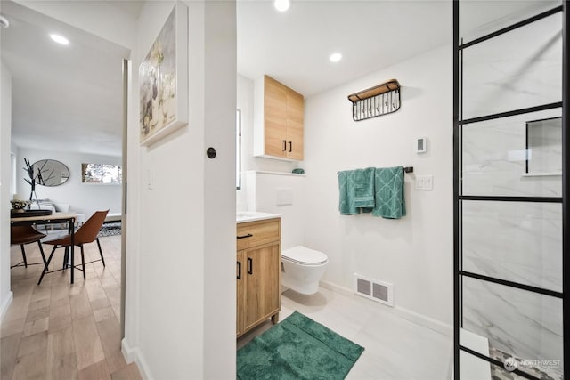 bathroom with walk in shower, vanity, toilet, and hardwood / wood-style floors