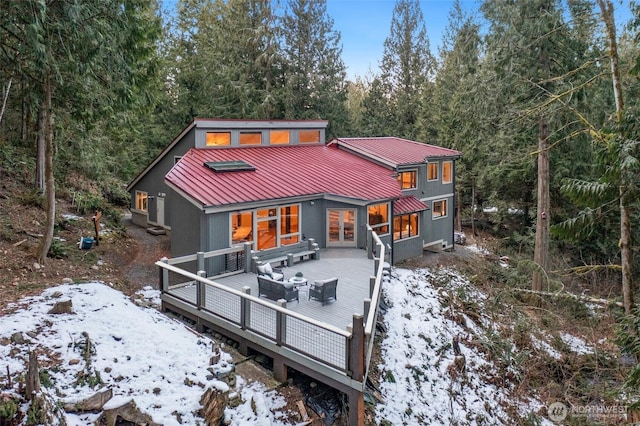 snow covered rear of property with a deck