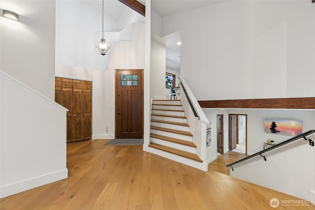 foyer entrance featuring hardwood / wood-style flooring, beam ceiling, a chandelier, and high vaulted ceiling