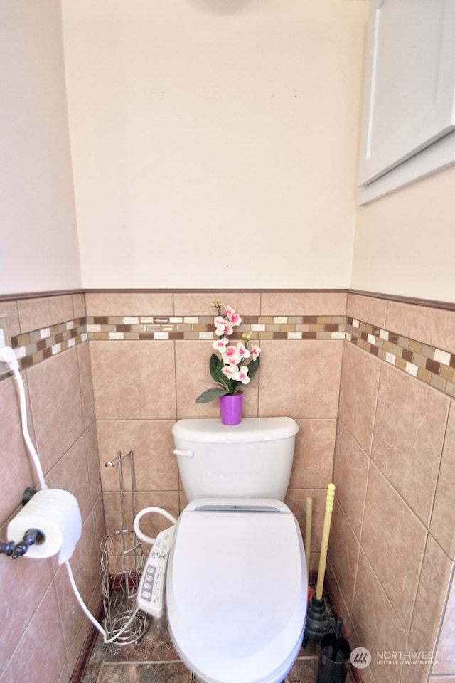 bathroom with toilet and tile walls