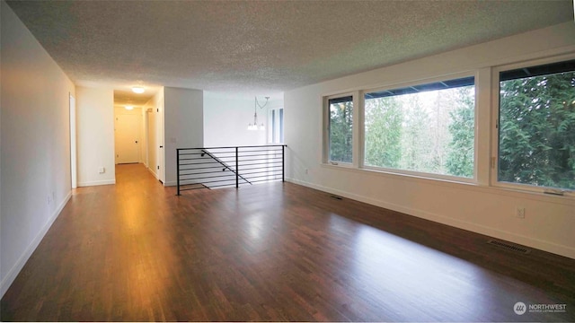 spare room featuring a textured ceiling and dark hardwood / wood-style floors