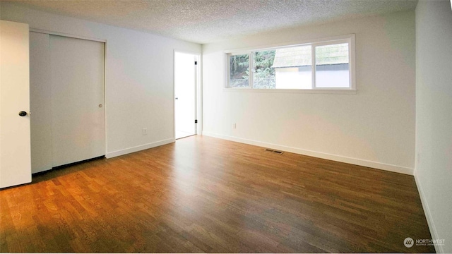 spare room with dark hardwood / wood-style floors and a textured ceiling