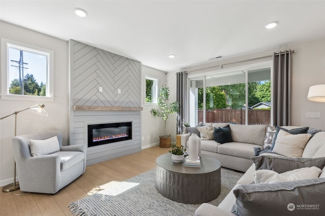 living room featuring a large fireplace and light hardwood / wood-style flooring