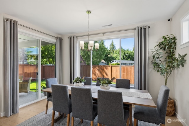 dining area featuring light wood-type flooring and an inviting chandelier