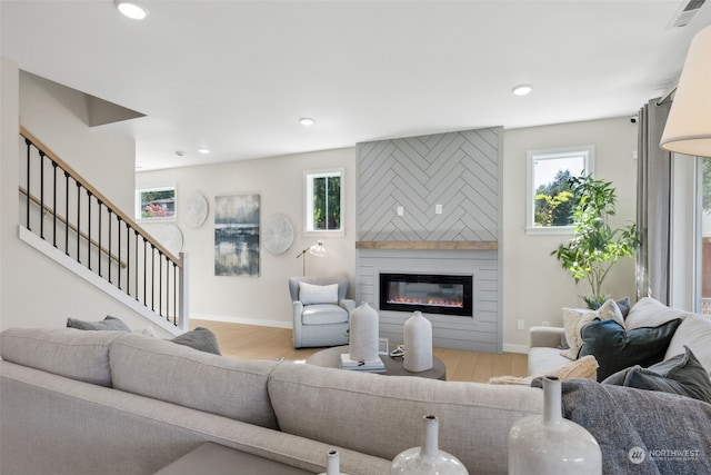 living room with a fireplace, light wood-type flooring, and a healthy amount of sunlight