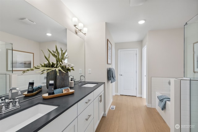 bathroom with a tub, vanity, and hardwood / wood-style flooring